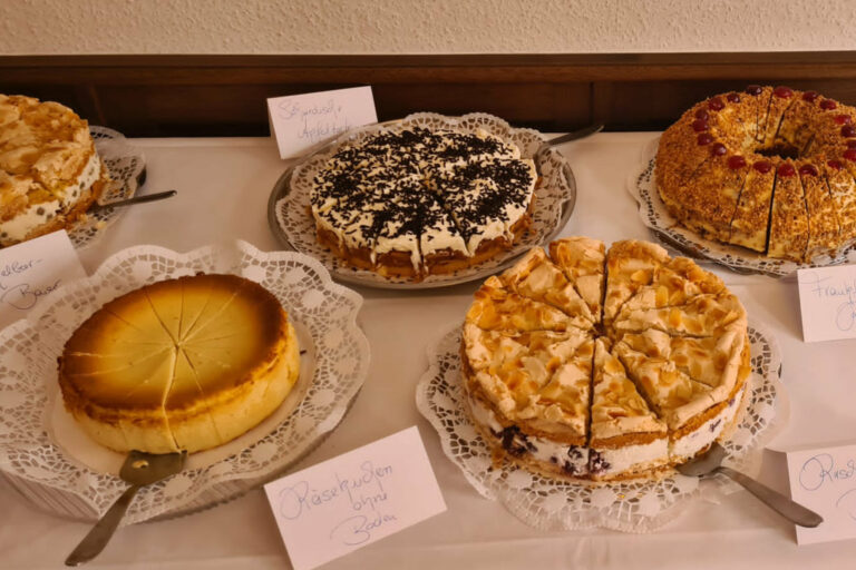 Verschiedene runde Kuchen und Torten eingedeckt auf weißer Tischdecke
